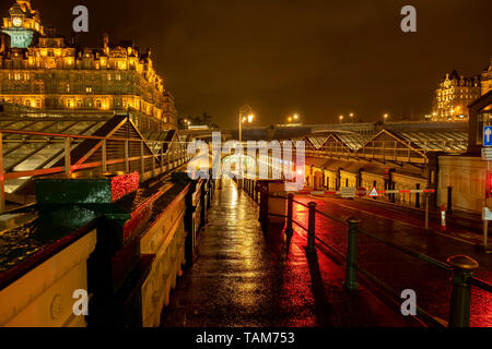 Bürgersteig und Straße Eingang der U-Bahn zum Bahnhof Waverley Station auf einem nassen Nacht, Edinburgh. Das Balmoral Hotel liegt im Hintergrund Stockfoto