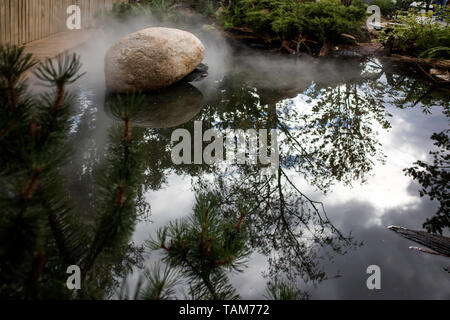 Große Boulder schmückt einen künstlichen Teich im Garten Stockfoto