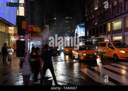 Mann auf bürgersteig Aufruf für eine von mehreren gelben Taxis außerhalb des Times Square - New York City Stockfoto