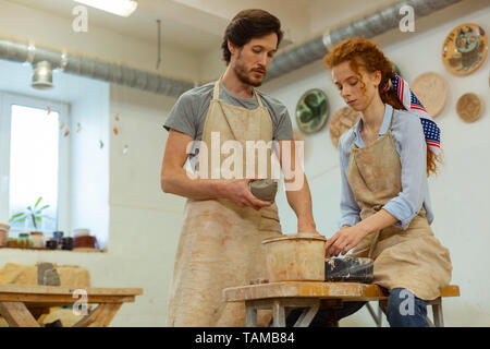 Master präsentiert Ton. Professionelles Ehepaar, das Arbeiten in ausgestattete Studio und halten frische Ton konzentriert Stockfoto