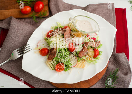 Salat mit gebratenem Fleisch, Radieschen, Kopfsalat, Tomaten, Käse und Gewürzgurken. Cafe Menü auf einer hölzernen Hintergrund in warmen Farben. Stockfoto