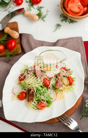 Salat mit gebratenem Fleisch, Radieschen, Kopfsalat, Tomaten, Käse und Gewürzgurken. Cafe Menü auf einer hölzernen Hintergrund in warmen Farben. Stockfoto