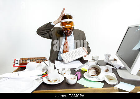 Konstanter Ausfall. Junger Mann verschüttete Getränke auf der Tastatur während der Arbeit und versucht aufzuwachen. Eine Menge Kaffee trinken. Konzept der "büroangestellter tr Stockfoto