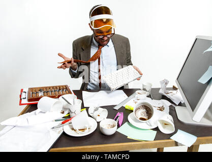 Konstanter Ausfall. Junger Mann verschüttete Getränke auf der Tastatur während der Arbeit und versucht aufzuwachen. Eine Menge Kaffee trinken. Konzept der "büroangestellter tr Stockfoto