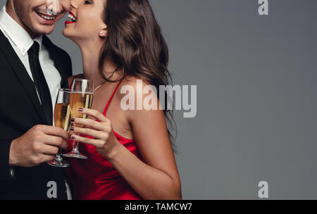 Nahaufnahme von Mann und Frau toasten Champagner Gläser. Romantisches Paar Getränke auf grauen Hintergrund. Stockfoto