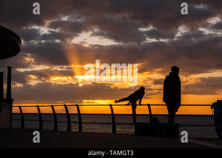 Aberystwyth Wales UK, Sonntag, 26. Mai 2019 Deutschland Wetter: Menschen bei Sonnenuntergang in Aberystwyth an einem kühlen Abend Silhouette kann, am Ende eines Tages des schweren Duschen und lange Perioden der Frühlingssonne auf der Westküste von Wales. Morgen Feiertag Montag, dürfte ein Tag der gemischten Bedingungen zu sein, mit der Gefahr, schwere thundery Duschen und eine frische Brise Photo Credit: Keith Morris/Alamy leben Nachrichten Stockfoto