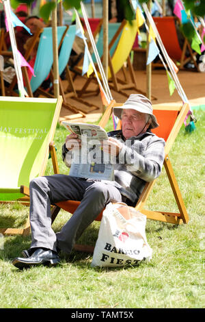 Hay Festival, Heu auf Wye, Powys, Wales, Großbritannien - Montag, 27. Mai 2019 - ein Besucher genießt eine Pause auf dem Festival Rasen zwischen Ereignissen und Lautsprecher an der Hay Festival an einem kühlen sonnigen breezy Feiertag Montag zu lesen. Foto Steven Mai/Alamy leben Nachrichten Stockfoto