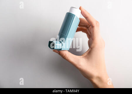 Weibliche hand mit Inhalator gegen Asthma auf hellen Hintergrund Stockfoto