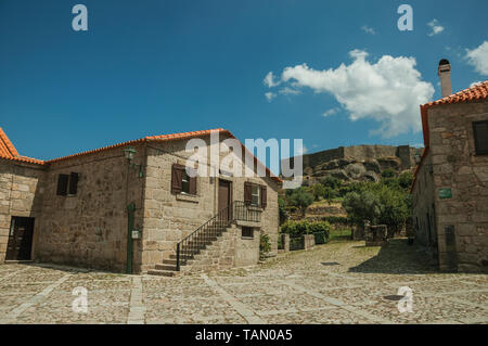 Altes Steinhaus auf der Gasse und die Burg auf dem Hügel in Gournes. Ein mittelalterliches Dorf mit einzigartiger Architektur in Osteuropa Portugal. Stockfoto