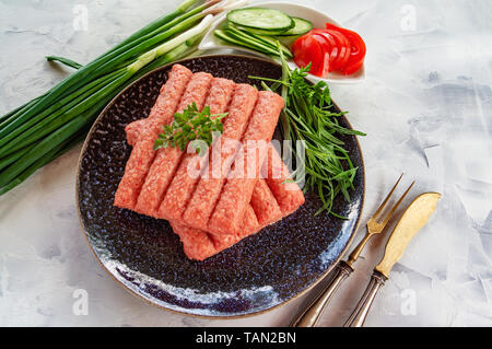 Chevapchichi ist eine nationale Balkan Teller. Nahaufnahme einer Reihe von frischem rohem Rindfleisch Döner auf schwarzem Teller. Kopieren Sie Platz. Stockfoto