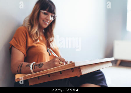 Freelancer zu Hause sitzen und schreiben. Nahaufnahme von einem kreativen Künstler eine Skizze sitzen auf dem Boden. Stockfoto