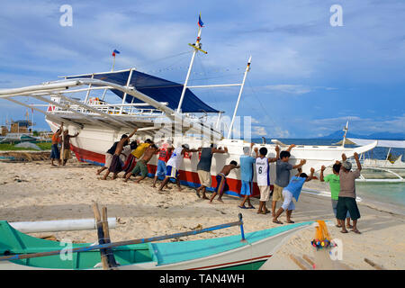 Fischer mit einem traditionellen Fischerboot nach Wartung vom Strand zum Meer, Bounty Beach, Insel Malapascua, Cebu, Philippinen Stockfoto