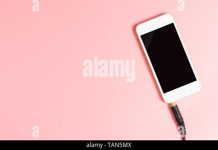 Verwendung des Smartphones als Music Player mit Kopfhörerausgang auf rosa Kopie Raum Stockfoto