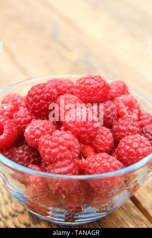 Reife Himbeeren in die Glasschale auf Holzplatten. Frische Beeren im Garten abgeholt Stockfoto