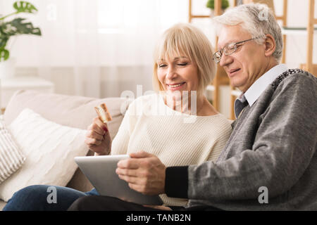 Online einkaufen. Ältere Paare mit Tablet und Kreditkarte Stockfoto