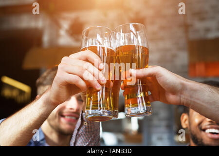 Beifall für uns. Männer trinken Bier und klirren Gläser Stockfoto