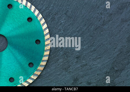Ein Teil der Diamant-trennscheibe von Smaragd Farbe, auf der rechten Seite der Kopie Raum gegen einen grauen Granit Hintergrund close-up. Stockfoto