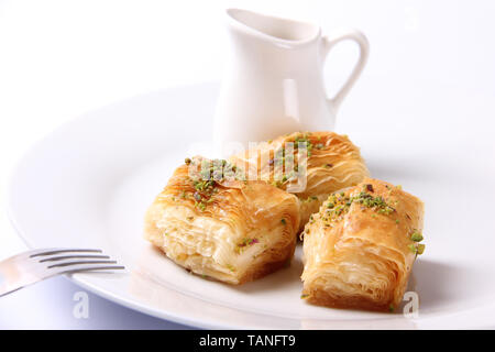 Detailansicht der Baklawa (Baklava) Platte, enthält drei Dreieck Baklava Stücke auf eine weiße, runde Platte, mit geerdetem Pistazien, Gabel gekleidet auf Stockfoto