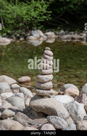 Ausgewogene Steine in der Nähe von einem Fluss und mit dem Wald im Hintergrund stack, Zen Meditation Wellness Entspannung Hintergrund Stockfoto