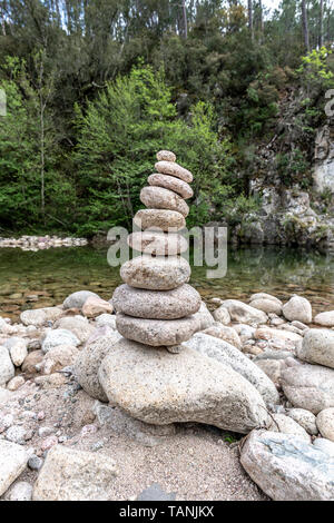 Ausgewogene Steine in der Nähe von einem Fluss und mit dem Wald im Hintergrund stack, Zen Meditation Wellness Entspannung Hintergrund Stockfoto