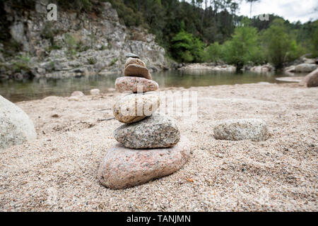 Ausgewogene Steine in der Nähe von einem Fluss und mit dem Wald im Hintergrund stack, Zen Meditation Wellness Entspannung Hintergrund Stockfoto