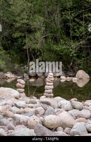 Ausgewogene Steine in der Nähe von einem Fluss und mit dem Wald im Hintergrund stack, Zen Meditation Wellness Entspannung Hintergrund Stockfoto