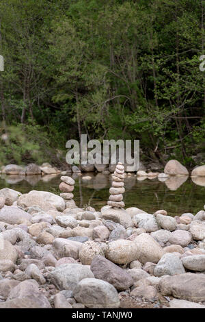 Ausgewogene Steine in der Nähe von einem Fluss und mit dem Wald im Hintergrund stack, Zen Meditation Wellness Entspannung Hintergrund Stockfoto