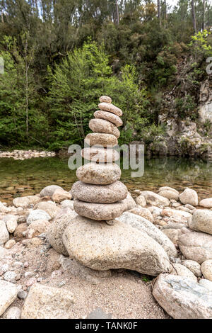 Ausgewogene Steine in der Nähe von einem Fluss und mit dem Wald im Hintergrund stack, Zen Meditation Wellness Entspannung Hintergrund Stockfoto