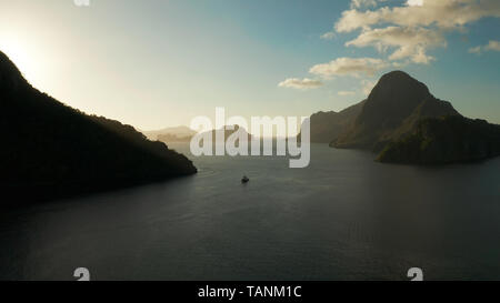 Luftaufnahme Tropical Bay in El Nido bei Sonnenuntergang. Marine mit Bergen und felsigen Inseln am Morgen Zeit. Sonnenuntergang über dem Meer. Sonnenuntergang Himmel und Berge Felsen der Bucht. Verträumt Sonnenuntergang unter den Felsen. Stockfoto