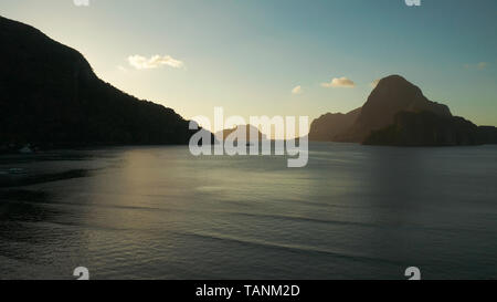 Luftaufnahme Tropical Bay in El Nido bei Sonnenuntergang. Marine mit Bergen und felsigen Inseln am Morgen Zeit. Sonnenuntergang über dem Meer. Sonnenuntergang Himmel und Berge Felsen der Bucht. Verträumt Sonnenuntergang unter den Felsen. Stockfoto