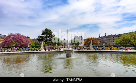 Der Brunnen in der Grand Bassin Rond der Jardin des Tuileries und dem Louvre im Hintergrund an einem sonnigen Frühlingstag Stockfoto