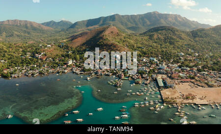 Luftaufnahme Coron Stadt mit Slums und Armenviertel. Hafen, Seebrücke, stadtbild Coron Town mit Booten auf Busuanga Island, Philippinen, Palawan. Marine mit Bergen. Stockfoto