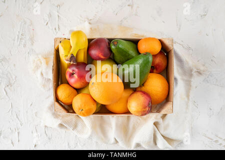 Große Holzkiste mit reifem Obst, Banane, Apfel, Orange, Mandarine, Avocado, vegetarische Essen Stockfoto