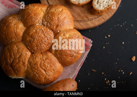 Frisch gebackene Weiche süße Brötchen geteilt mit Sesam, abgerissene Stück Brot Stockfoto