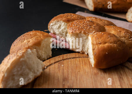 Frisch gebackene Weiche süße Brötchen geteilt mit Sesam, abgerissene Stück Brot Stockfoto