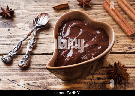 Schokoladencreme mit Zimt und Anis. Fondue mit Schokolade auf einem Holztisch Stockfoto