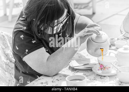 Mädchen mit Down-syndrom Leben genießen und gießen Sie eine Tasse Tee. Stockfoto