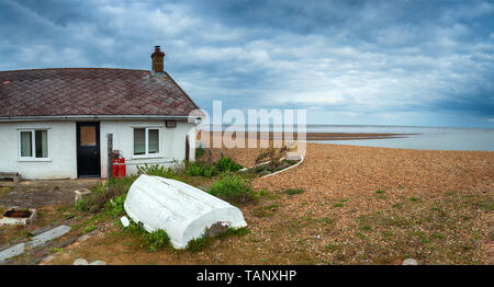 Ein Ferienhaus am Strand unter einem Moody Himmel bei Kies Straße auf der Küste von Suffolk Stockfoto