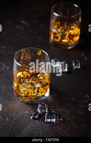 Zwei Gläser Whisky mit Eis auf dunklem Hintergrund mit Reflexion. Alcohok trinken Stockfoto