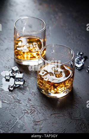 Zwei Gläser Whisky mit Eis auf dunklem Hintergrund mit Reflexion. Alcohok trinken Stockfoto