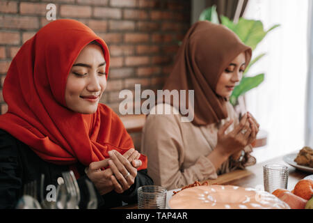 Hijab Frauen zusammen beten vor dem Essen Stockfoto