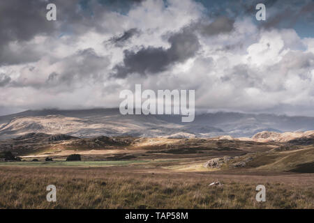 Niedrige Wolken über Berggipfel und Sonnenlicht Patches auf Hügeln. Panoramablick auf majestätische Tal in den Lake District. idyllische Landschaft. Reisen. Stockfoto
