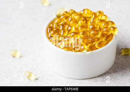 Fischöl Kapseln (Omega 3) in einer weißen Schüssel auf einem grauen Hintergrund. Stockfoto