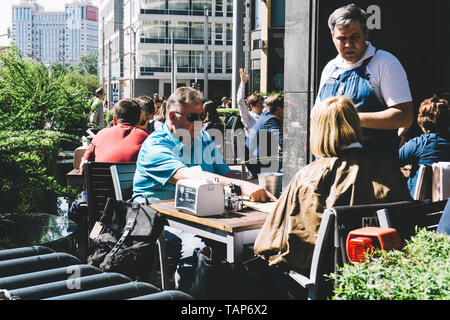 Moskau, Russland - 27. Mai 2019: Cafe Gäste machen eine Bestellung mit einem Kellner auf den Straßen von Moskau. Stockfoto