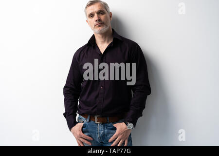 Fröhlicher Mann mittleren Alters vor weißem Hintergrund, in Jeans und schwarzem Hemd, Mitte geschossen Stockfoto