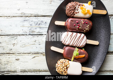 Vanille Eis am Stiel mit Schokolade überziehen und Top mit Mandeln Nüsse und Bonbons auf weißen Hintergrund. Stockfoto