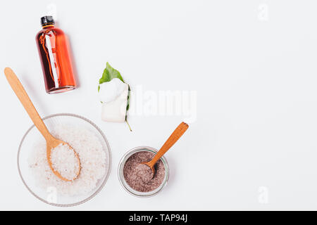 Spa Cosmetics auf weißem Hintergrund mit Kopie Raum, flach. Kaffee Peeling, Meersalz, Seife und eine Flasche Öl, Ansicht von oben. Stockfoto