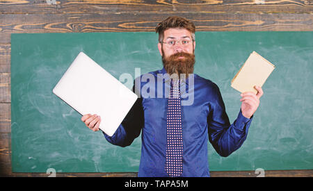 Lehrer bärtigen Hipster hält Buch und Laptop. Mit der rechten Lehre Methode wählen. Moderne statt überholt. Lehrer mit modernen pädagogischen Ansatz. Moderne Technologien profitieren. Digitale gegen Papier. Stockfoto