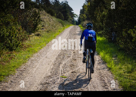 Reife weibliche Radfahrer reiten durch Wald in Dänemark. Stockfoto