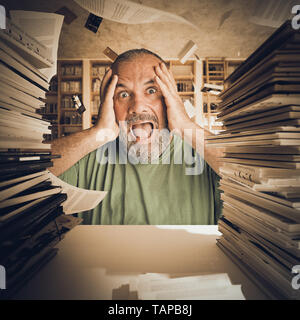 Portrait eines bärtigen Mannes durch zu viel Studie betonte, Stapel der Bücher und Papiere im Hintergrund fliegen. Stockfoto